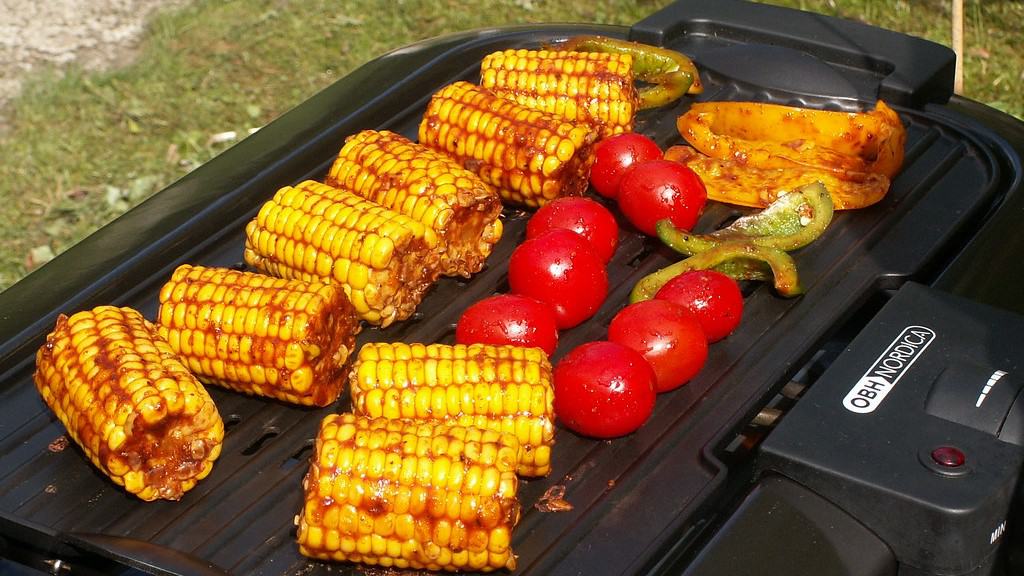 Corn and tomatoes grilling on an electric BBQ